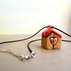 a small wooden house with a heart painted on it's roof is attached to a chain