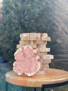 a stack of wood logs sitting on top of a wooden table next to a bush