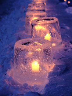 some ice cubes are lined up in the snow with lit candles on them,