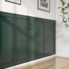 an empty room with green cabinet doors and pictures on the wall above it, next to a plant in a vase