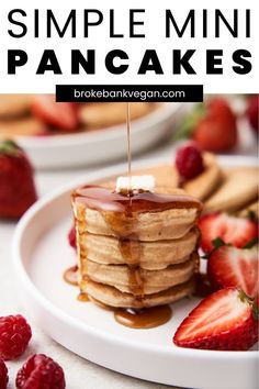 a stack of pancakes with syrup on top and strawberries around the edges in front