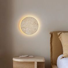 a bedroom with a round light on the wall and a small table in front of it