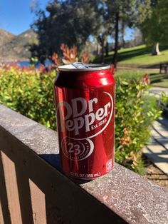 a can of soda sitting on top of a wooden fence