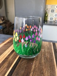 a painted glass sitting on top of a wooden table