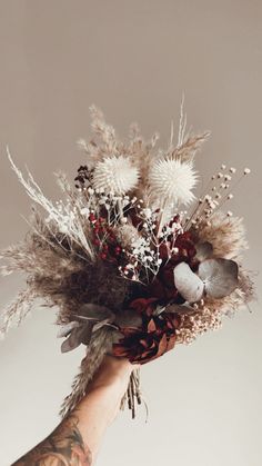 a person's hand holding a bouquet of dried flowers