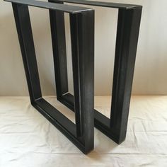 two black metal frames sitting on top of a white tablecloth covered floor next to each other