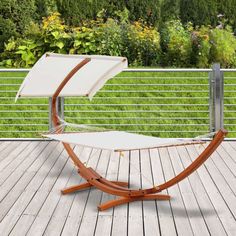 an outdoor hammock on a deck with grass and flowers in the back ground