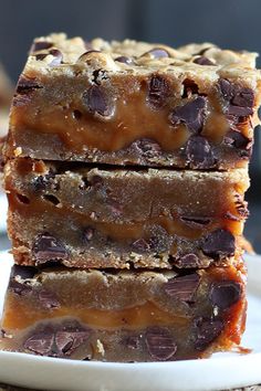 three pieces of chocolate chip cookie bars stacked on top of each other in front of a plate