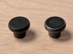 two black knobs sitting on top of a wooden table