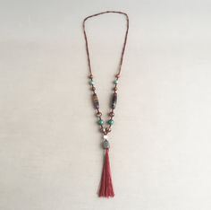 A beautiful oriental necklace consisting of several  semi precious polished stone beads including Jade and Tigers eye. Held on a burgandy hand knotted silk cord and ending in a silk tassel. Pleasingly weighty, A truly beautiful piece to wear and display. Supplied in a gift box Jade has long been considered to be a lucky stone Green Jade is believed to bring tranquility to the spirit and calm wisdom to the mind. Tigers Eye is a crystal with lovely bands of yellow-golden colour through it. A power Adjustable Spiritual Tassel Necklaces, Spiritual Tassel Necklaces With Adjustable Fit, Bohemian Hand Knotted Necklace For Rituals, African Beads Necklace, Tube Necklace, Golden Colour, Lucky Stone, Silk Cord, African Beads