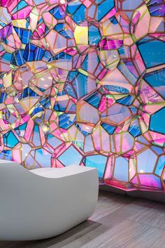 a white chair sitting in front of a colorful wall with lots of mirrors on it