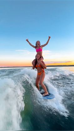 two women are riding on the back of a surfboard