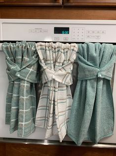 three teal towels hanging from the front of an oven