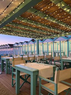 an outdoor dining area with tables and chairs, lights strung from the ceiling above them