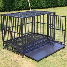 a black dog cage sitting in the grass