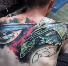 the back of a man's upper half with an alien ship tattoo on it