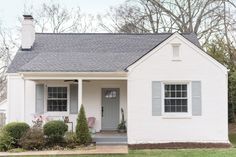 a white house with blue shutters and a gray door on the front porch is shown