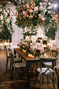 a table with candles and flowers on it is surrounded by greenery in the center