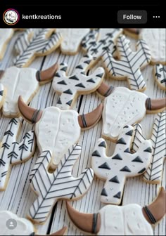 decorated cookies are arranged on a table with white and black designs, including arrows and snowflakes