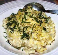 a white plate topped with mashed potatoes covered in herbs