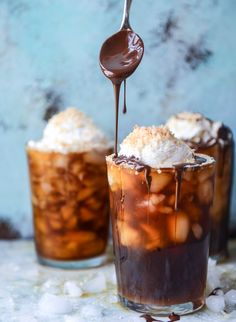 two glasses filled with ice cream and caramel on top of each other, one being drizzled with chocolate