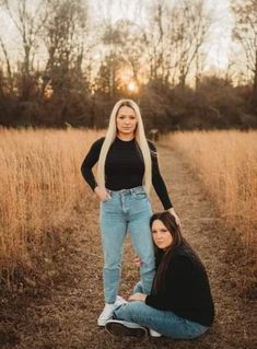 two women sitting on the ground with their arms around each other, posing for a photo