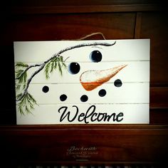 a wooden sign that says welcome with an image of a snowman's face