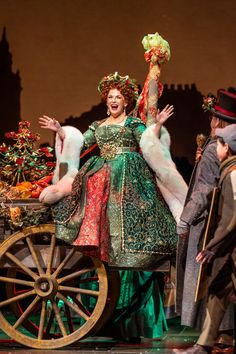 a woman in green and red dress standing on top of a wagon