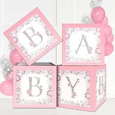 pink and white baby blocks with balloons in the background, one is for a girl