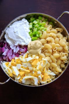 an assortment of pasta and vegetables in a bowl on a table top with a spoon