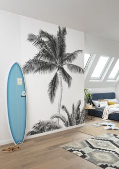 a surfboard leaning against a wall in a room with a bed and rug on the floor