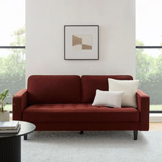 a living room with a red couch and two white pillows