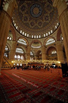 the inside of an ornate building with many windows and rugs on the floor in front of it