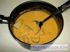 a pan filled with yellow soup on top of a stove next to a spatula