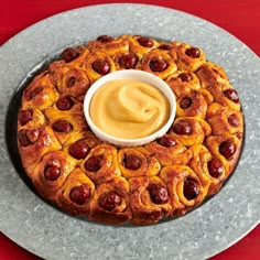 a plate topped with a pastry covered in cinnamon buns and dip sauce on top