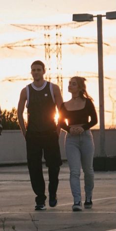 two people walking down the street at sunset