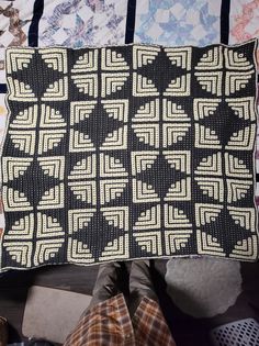 a black and white quilt sitting on top of a bed next to a pile of pillows