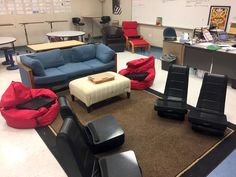 a room with several chairs, couches and tables on the floor in front of a whiteboard