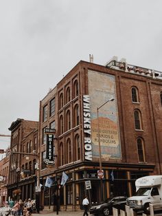 an old brick building on the corner of a street with cars parked in front of it