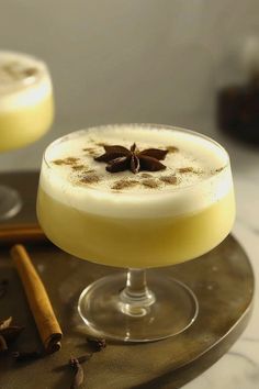 an alcoholic drink with cinnamon garnish on the rim next to two glasses filled with liquid