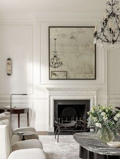 a living room filled with furniture and a chandelier above a fire place in front of a fireplace