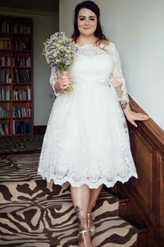 a woman in a white dress is standing on some stairs and holding a bunch of flowers