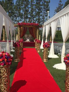 a red carpeted aisle with white drapes and gold pillars decorated with colorful flowers