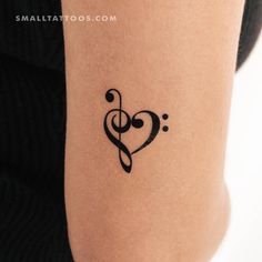 a small tattoo on the arm of a woman with a treble in the shape of a heart