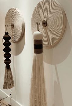 two wall hangings with tassels attached to them on the side of a wall