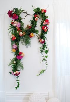 an arrangement of flowers and greenery on a white wall