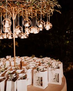 a table with bags and lights hanging from it's branches, on which there are small vases filled with flowers