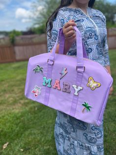 a woman holding a purple bag that says mary on the front and letters mary on the back