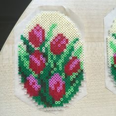 two pieces of beaded art with red flowers on them, one is made out of plastic beads