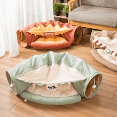 two pet beds on the floor in front of a couch and chair, one with a cat toy